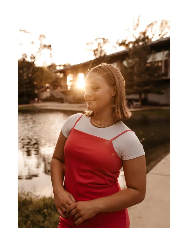 Woman in red dress by lakeside at sunset