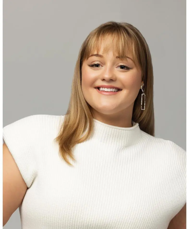 Smiling woman wearing white sweater and earrings