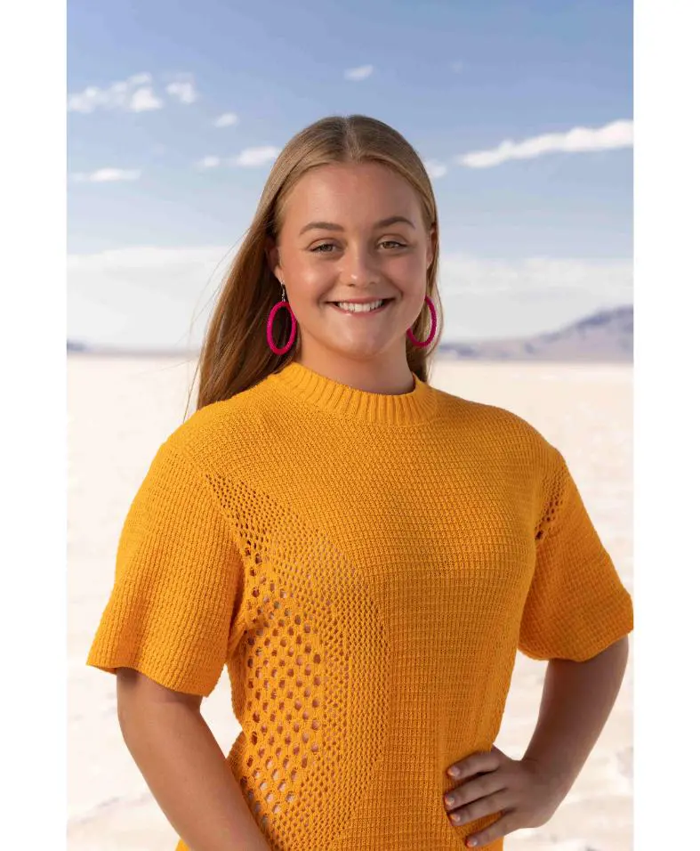 Smiling woman in orange sweater at salt flat