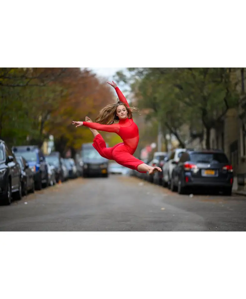 Dancer in red leaping across city street