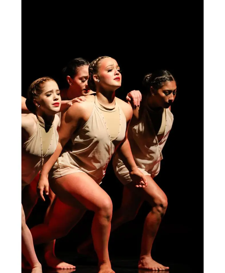 Four dancers in beige costumes performing onstage