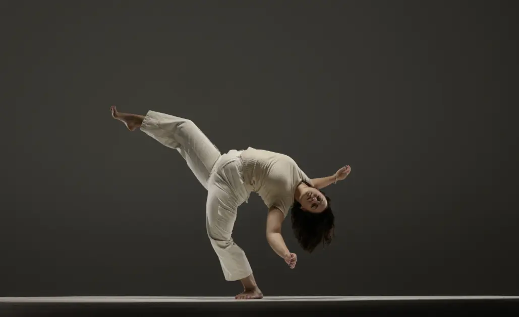 Dancer balancing on one foot in beige outfit