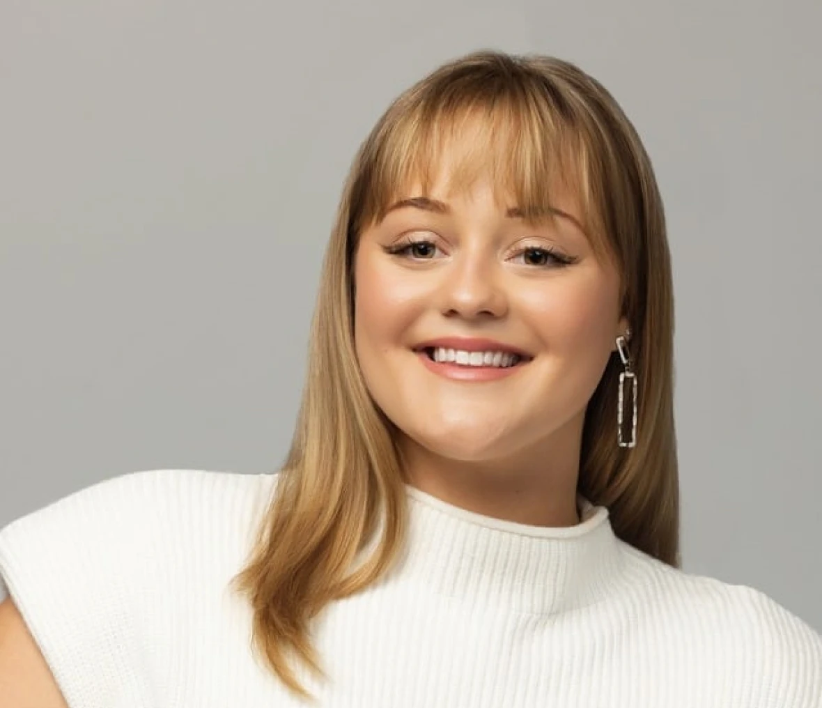 Smiling woman with bangs wearing white top